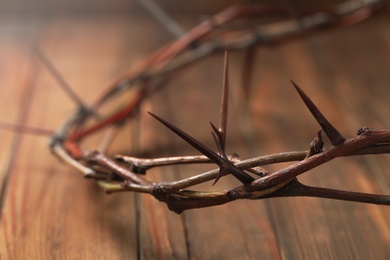 Photo of Crown of thorns on wooden table, closeup. Easter attribute