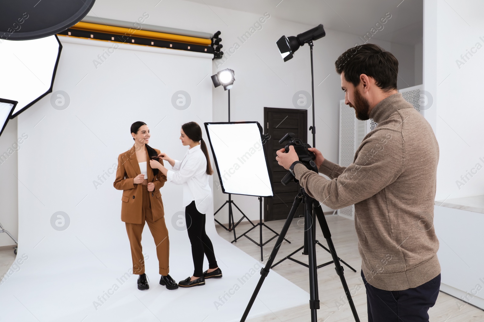 Photo of Professional photographer and stylist working with beautiful model in modern photo studio