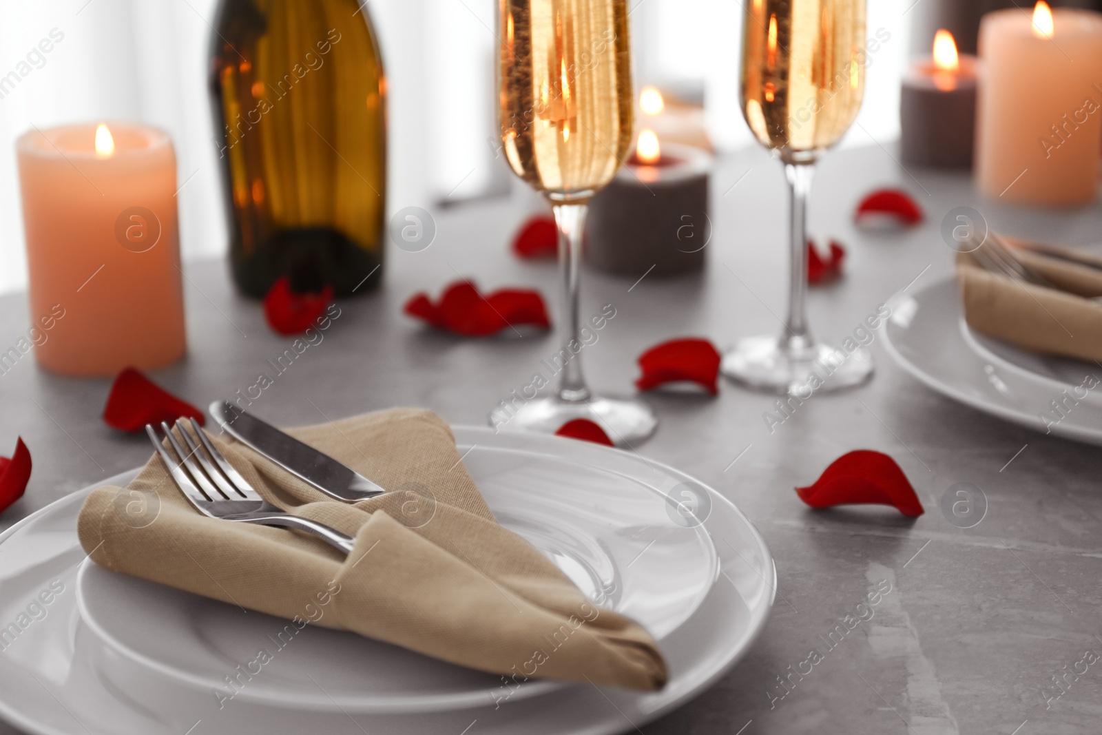 Photo of Romantic table setting with burning candles and rose petals indoors