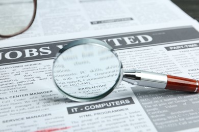 Photo of Magnifying glass on newspaper. Job search concept