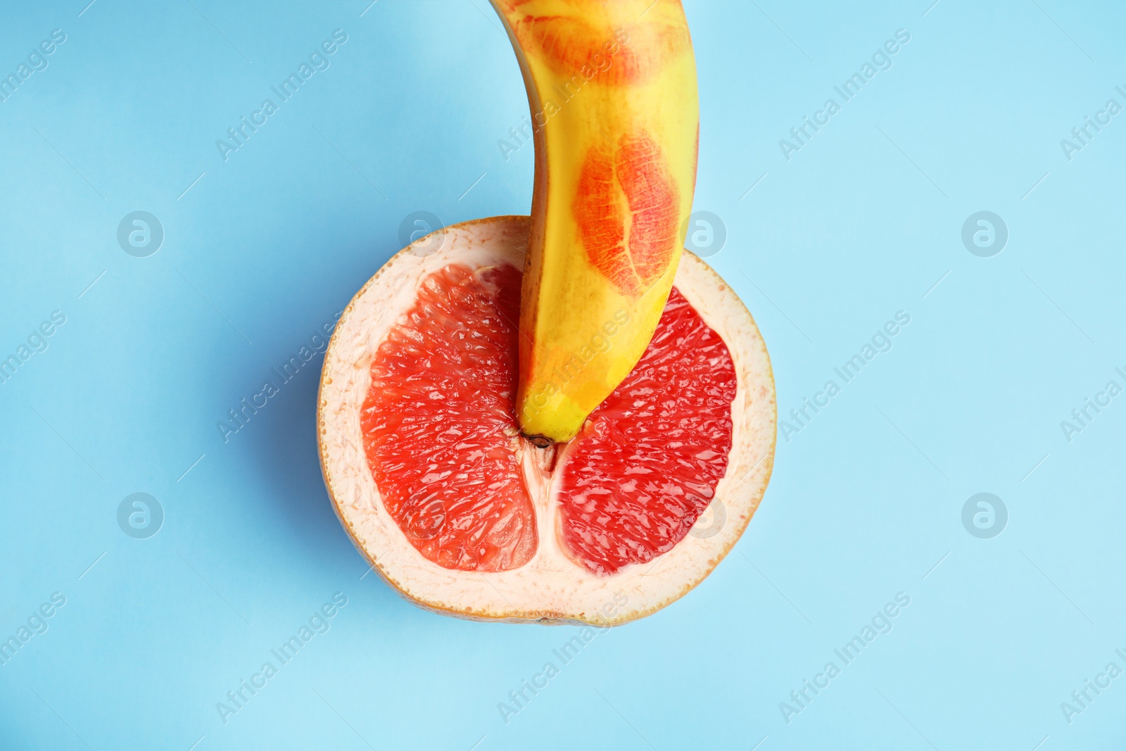 Photo of Flat lay composition with fresh banana and grapefruit on blue background. Sex concept