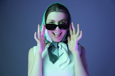 Photo of Portrait of beautiful young woman with sunglasses on color background with neon lights