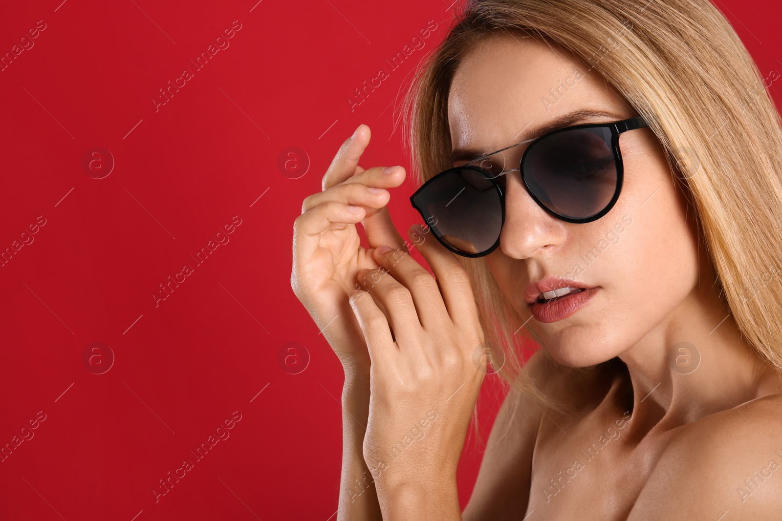 Photo of Beautiful woman in stylish sunglasses on red background. Space for text