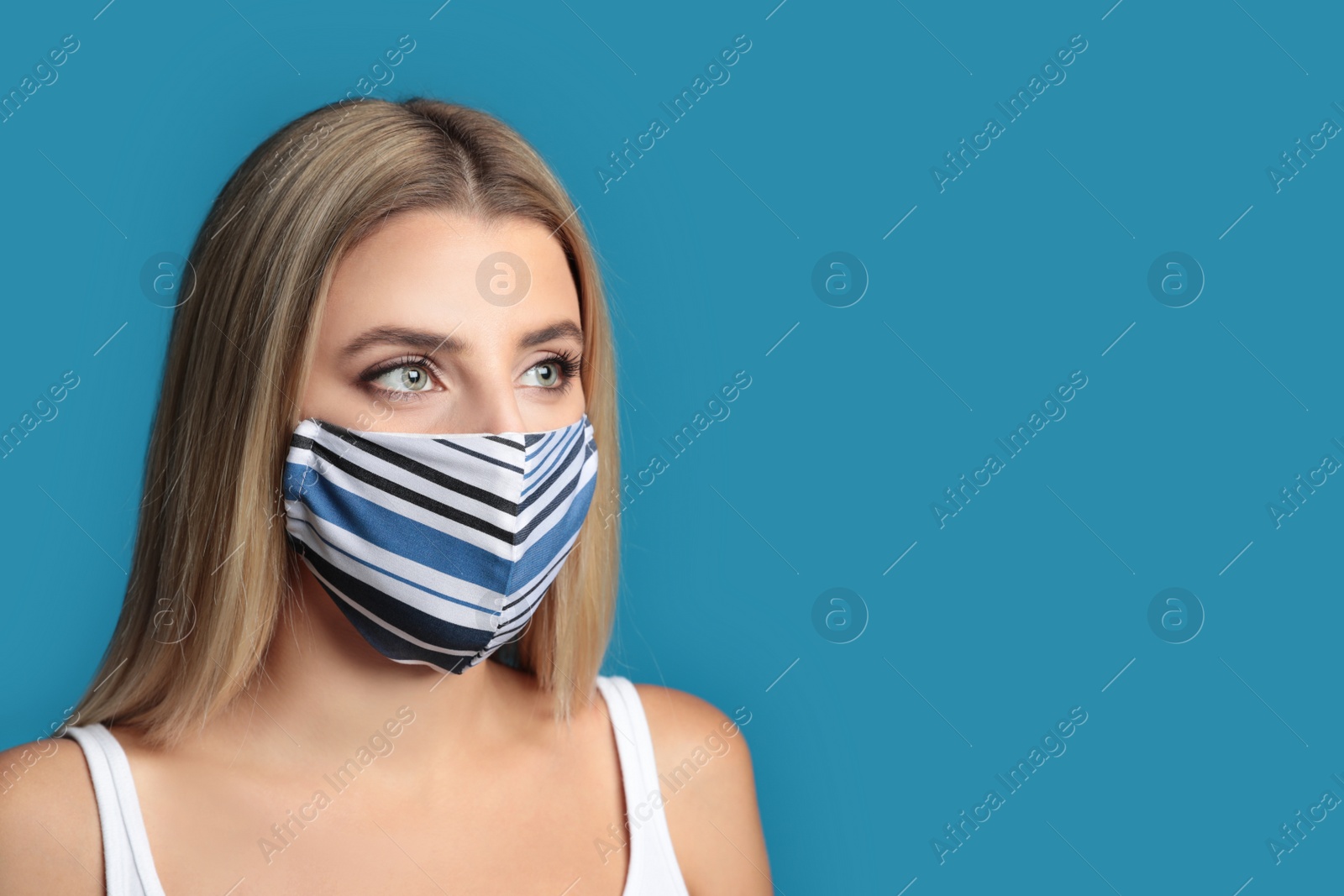 Photo of Young woman in protective face mask on blue background. Space for text