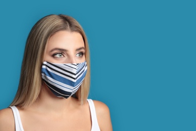 Young woman in protective face mask on blue background. Space for text