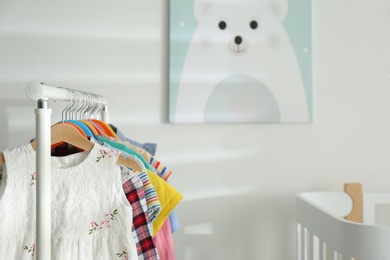 Different clothes hanging on rack in bedroom. Space for text