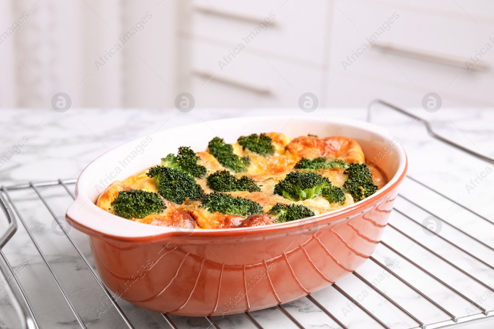 Photo of Tasty broccoli casserole in baking dish on cooling rack