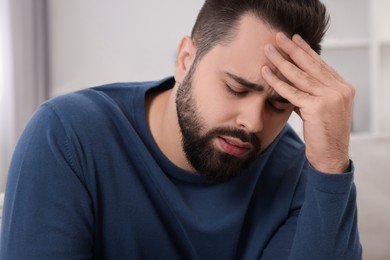 Unhappy man suffering from headache at home