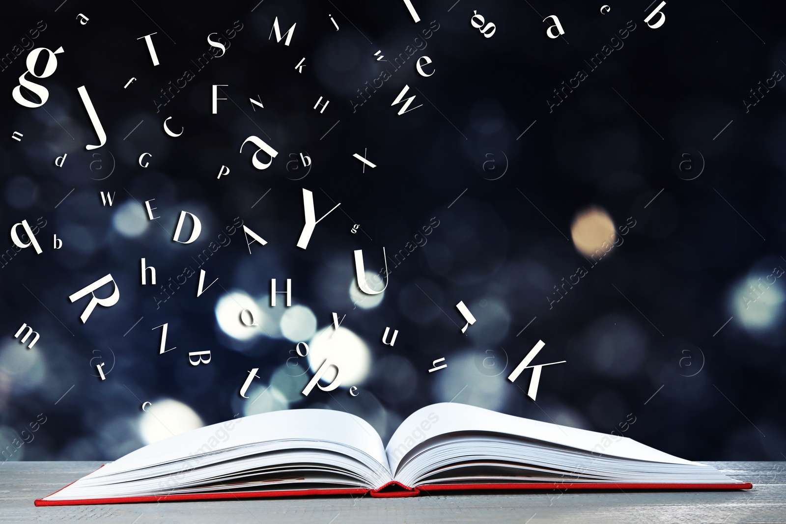 Image of Letters flying out from open book on wooden table, bokeh effect