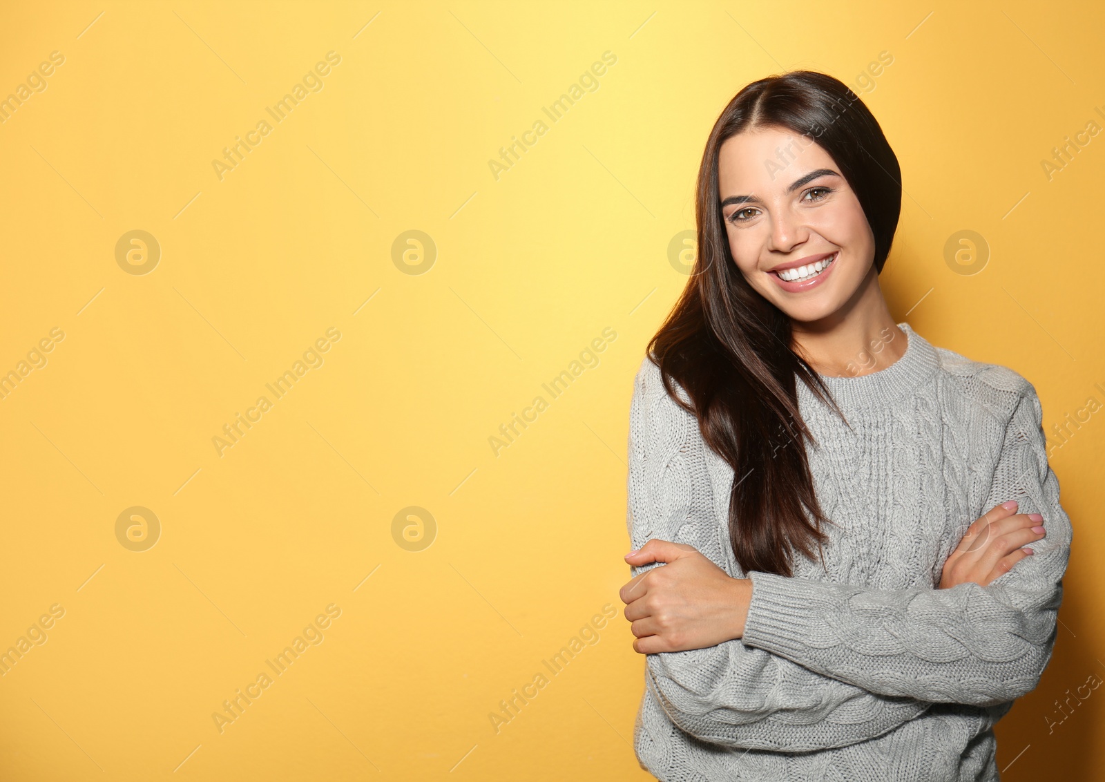 Image of Happy young woman wearing warm sweater on yellow background. Space for text