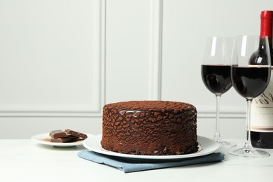 Photo of Delicious chocolate truffle cake and red wine on white marble table