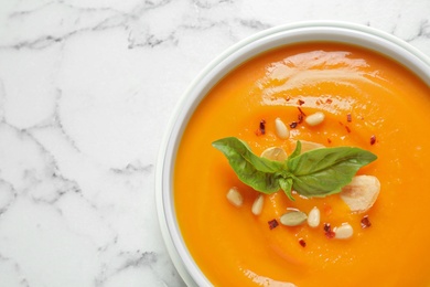 Delicious pumpkin soup in bowl on marble table, top view. Space for text
