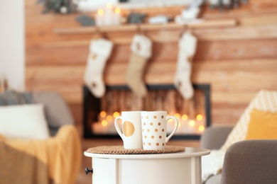 Cups on white table in decorated living room. Christmas interior