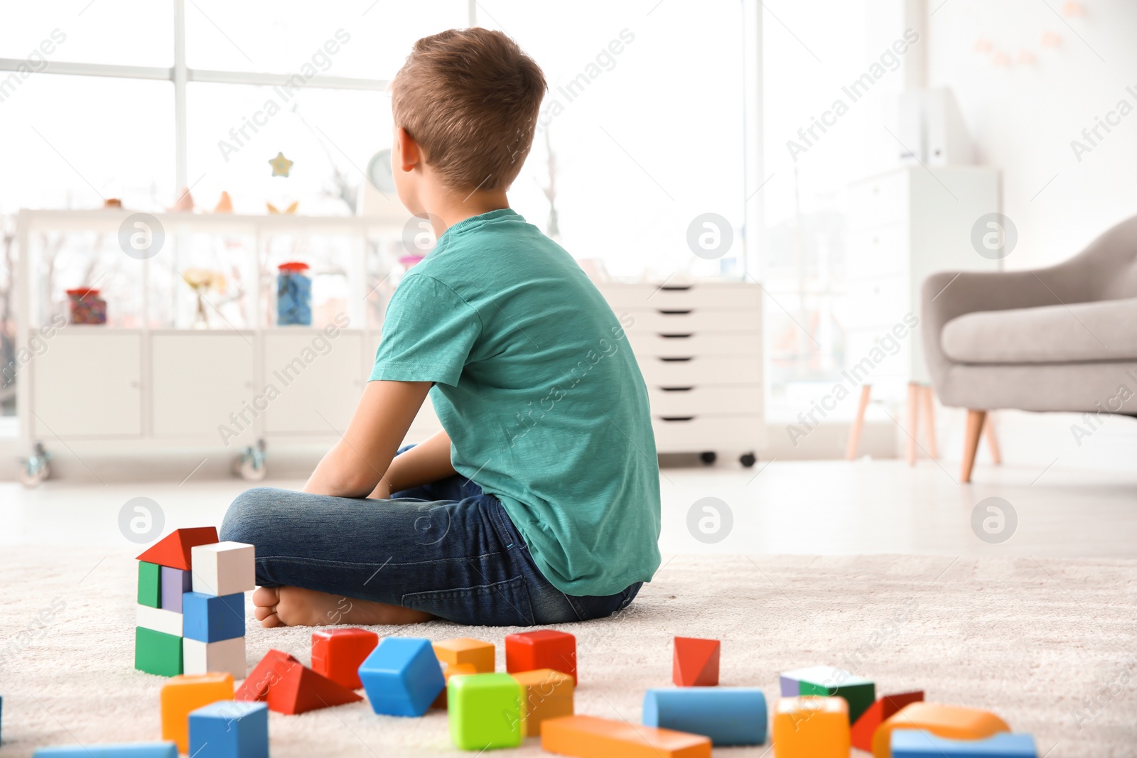 Photo of Little autistic boy playing with cubes at home