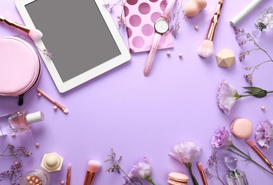 Frame made with tablet and beauty blogger's accessories on lilac background, top view. Space for text