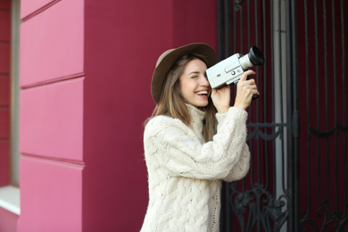 Beautiful young woman with vintage video camera on city street