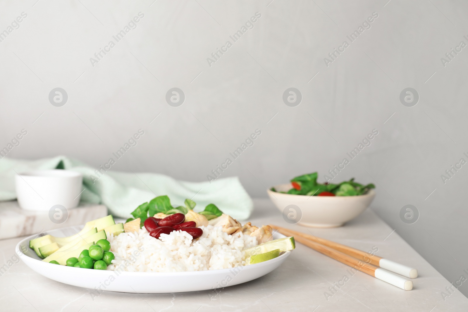 Photo of Plate of boiled rice with vegetables and meat on table. Space for text