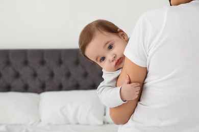 Mother holding her adorable baby in bedroom. Space for text