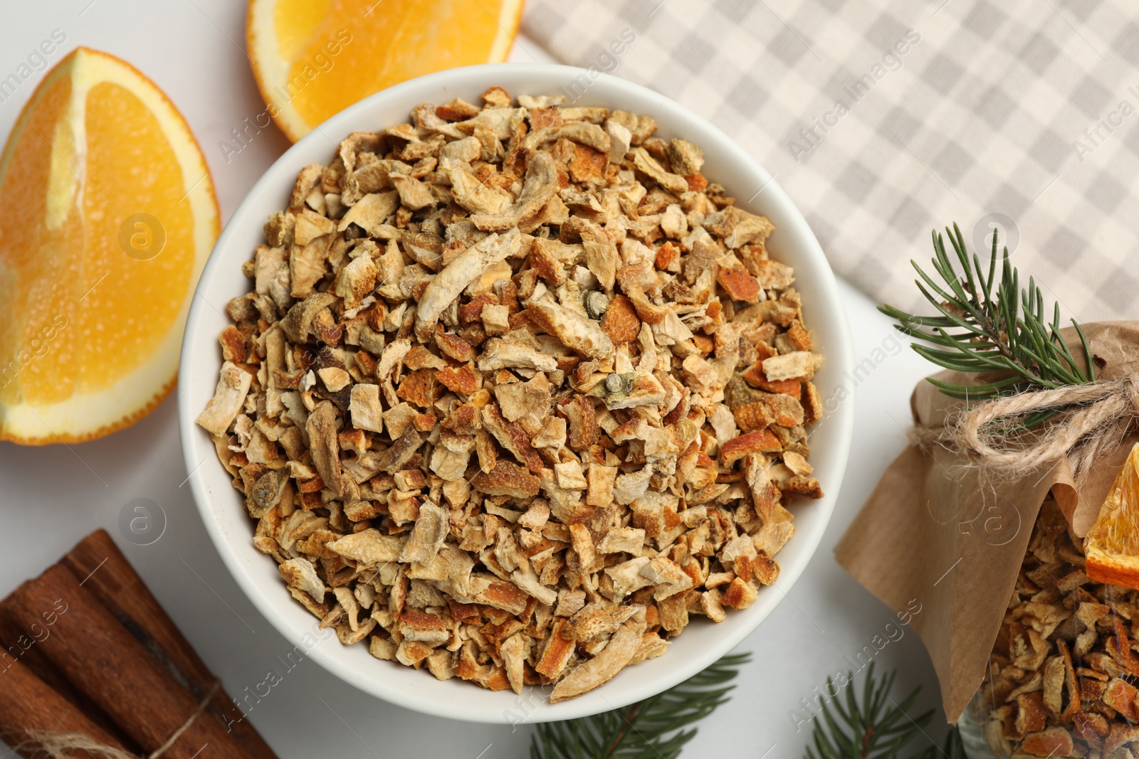 Photo of Bowl of dried orange zest seasoning, fresh fruit and cinnamon on white marble table, flat lay