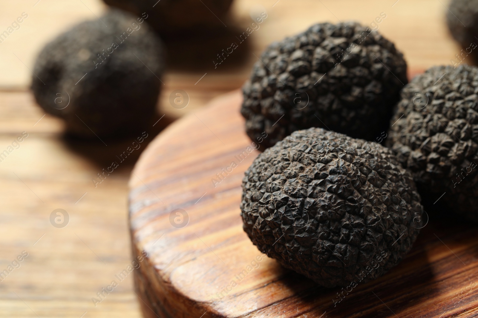 Photo of Black truffles with wooden board on table, closeup