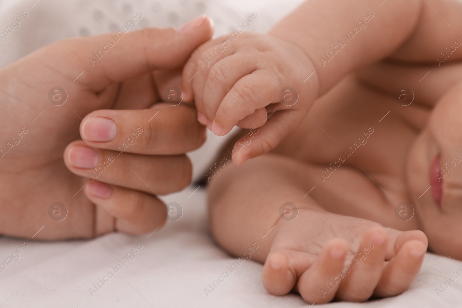 Photo of Mother with her cute baby on bed, closeup of hands