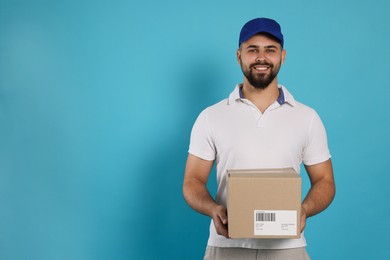 Photo of Courier holding cardboard box on light blue background, space for text