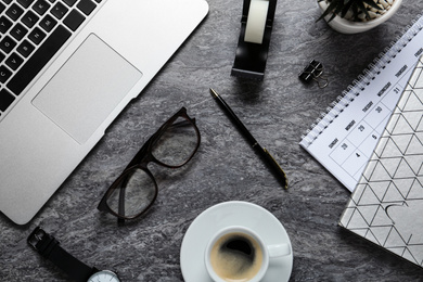 Photo of Flat lay composition with laptop, glasses and stationery on dark grey table