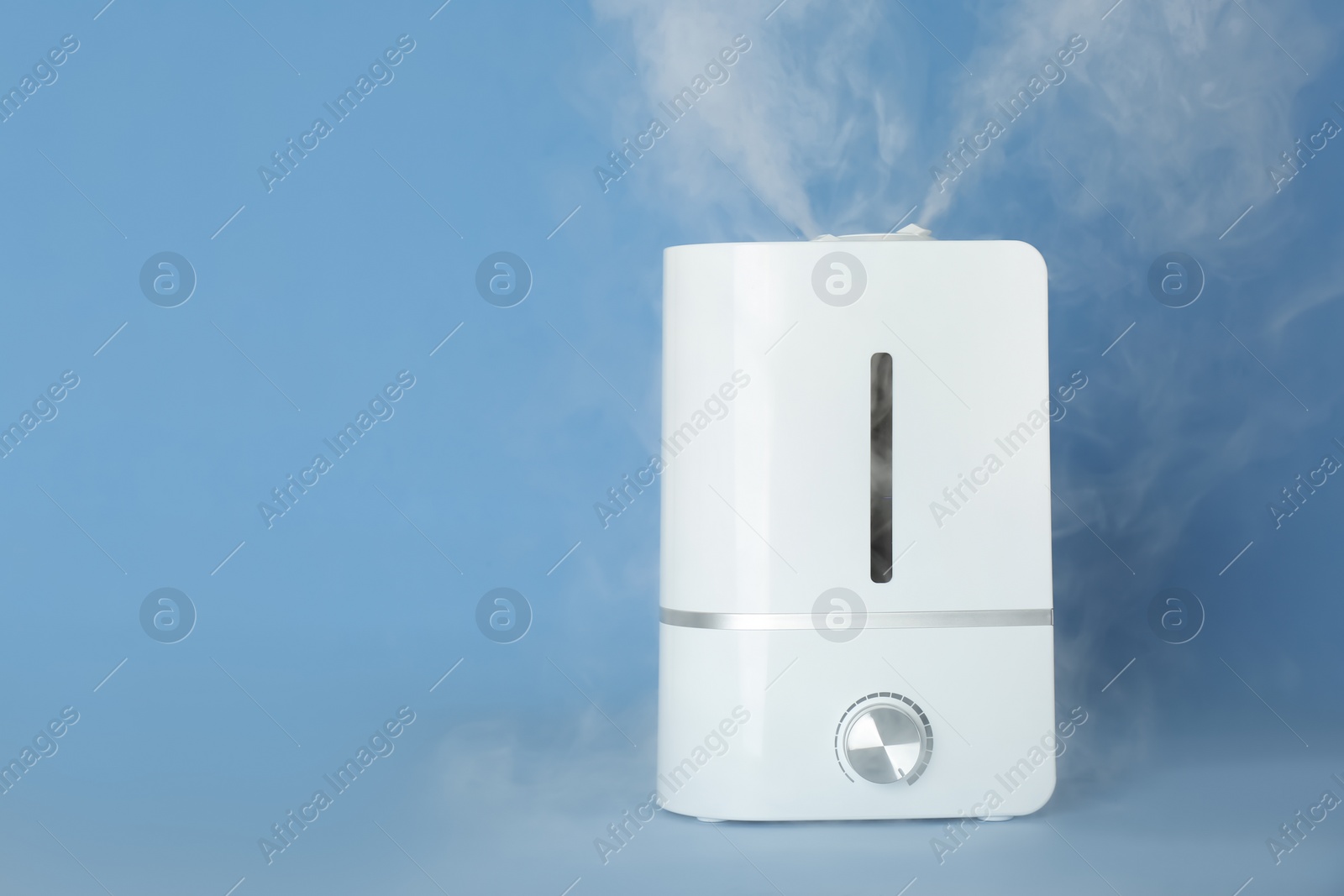 Photo of Modern air humidifier on light blue background. Space for text