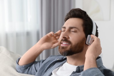Photo of Handsome man listening music with headphones indoors