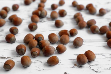 Tasty hazelnuts on white wooden table, closeup