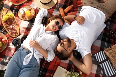Happy young couple resting on picnic plaid, above view