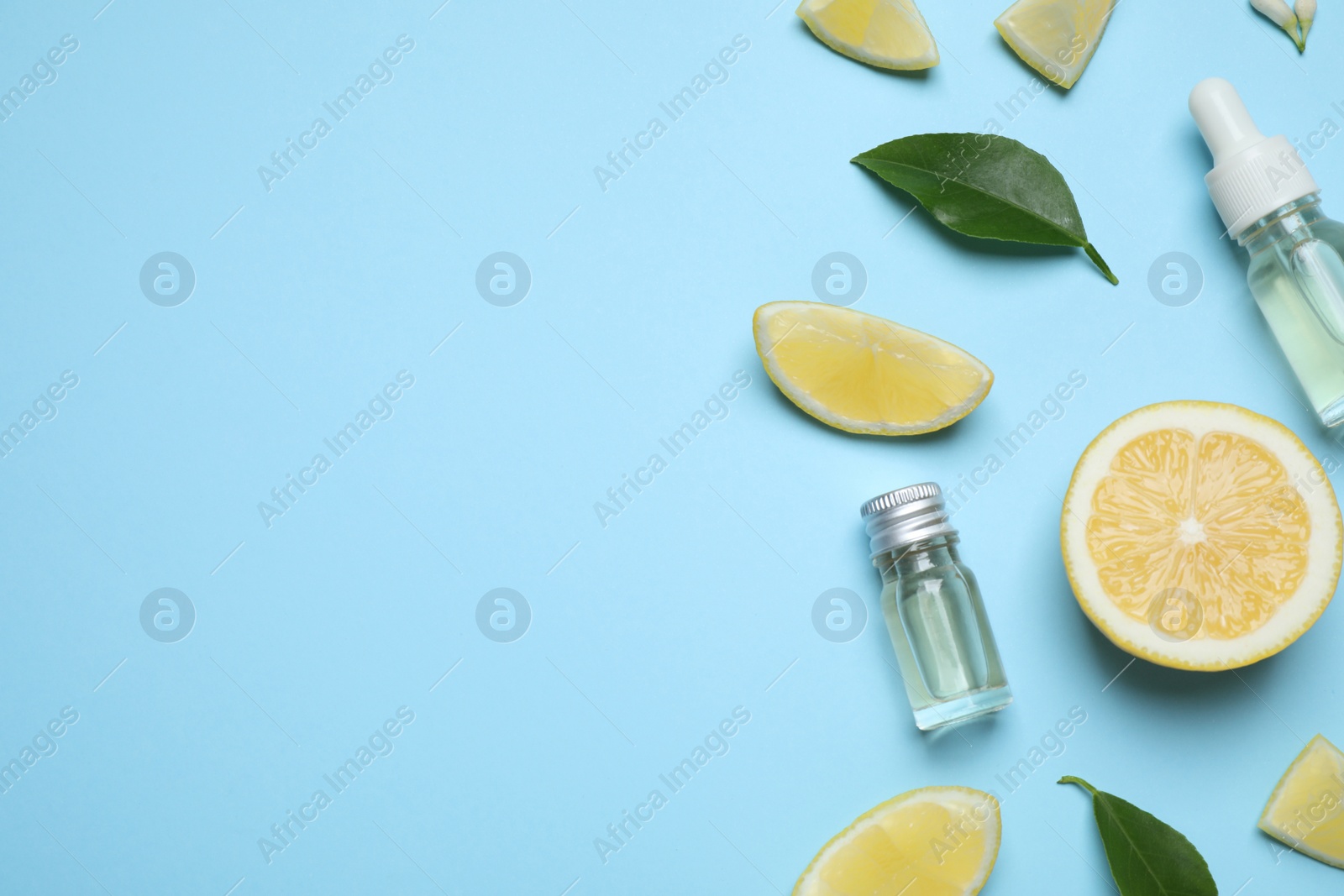 Photo of Flat lay composition with bottles of citrus essential oil on light blue background. Space for text