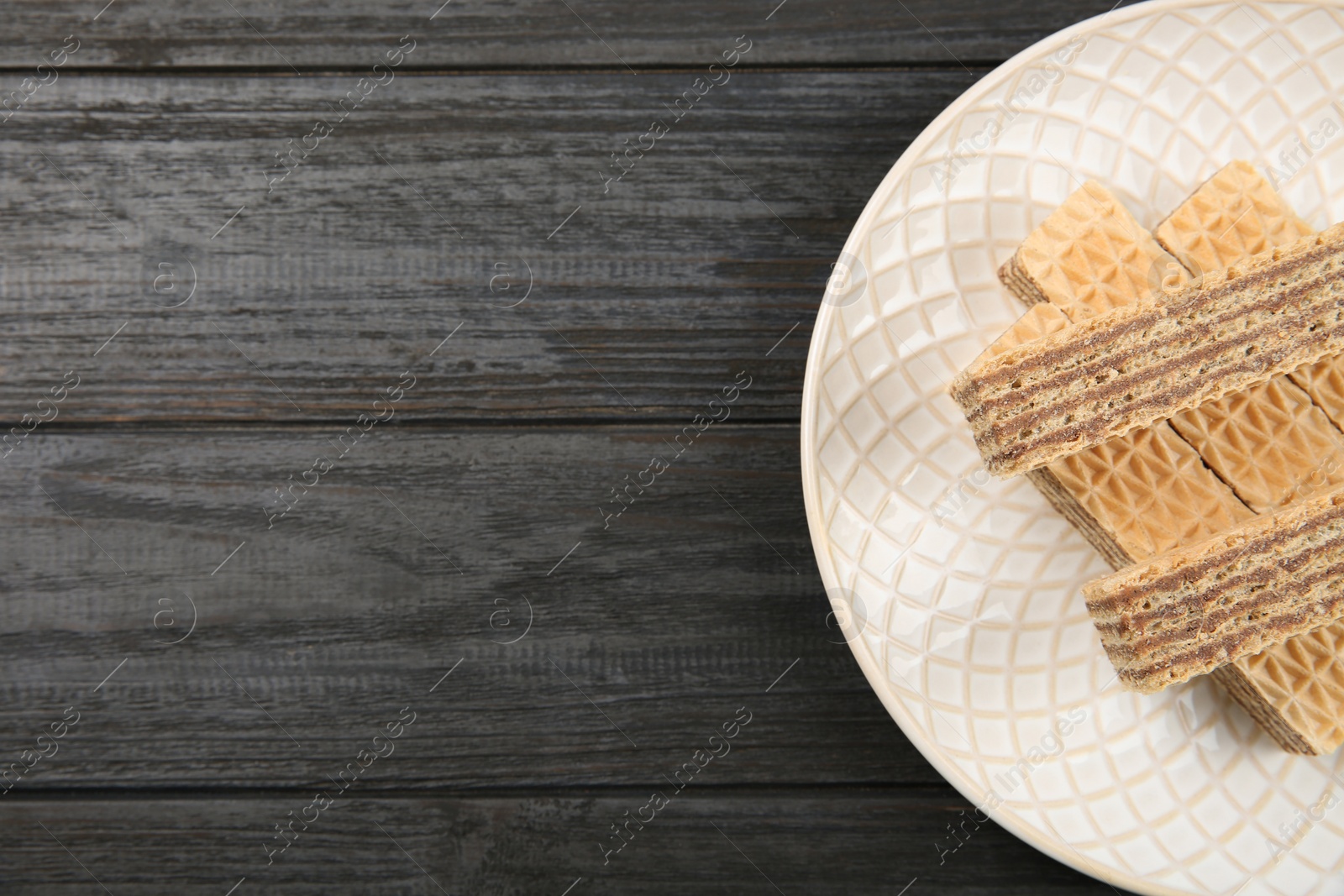 Photo of Plate with delicious crispy wafers on wooden table, top view. Space for text