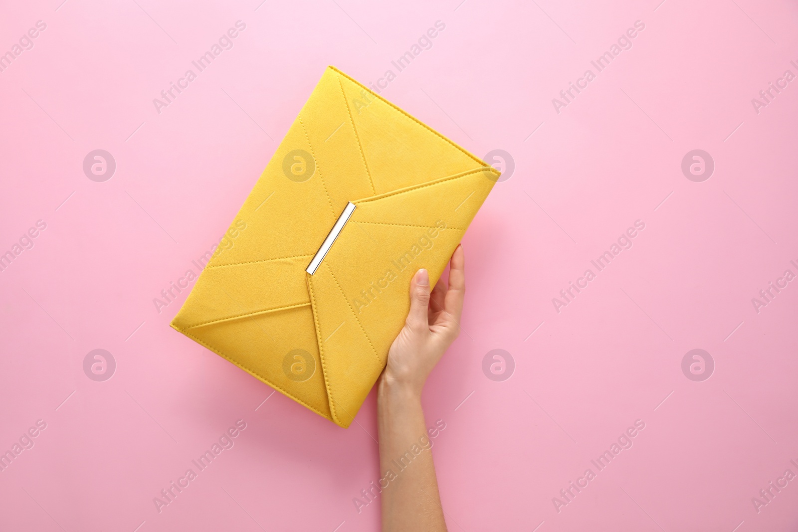 Photo of Woman holding stylish envelope bag on pink background, closeup