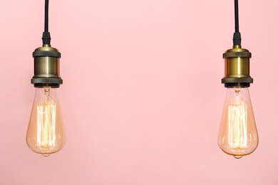 Photo of Pendant lamps with light bulbs on color background, space for text