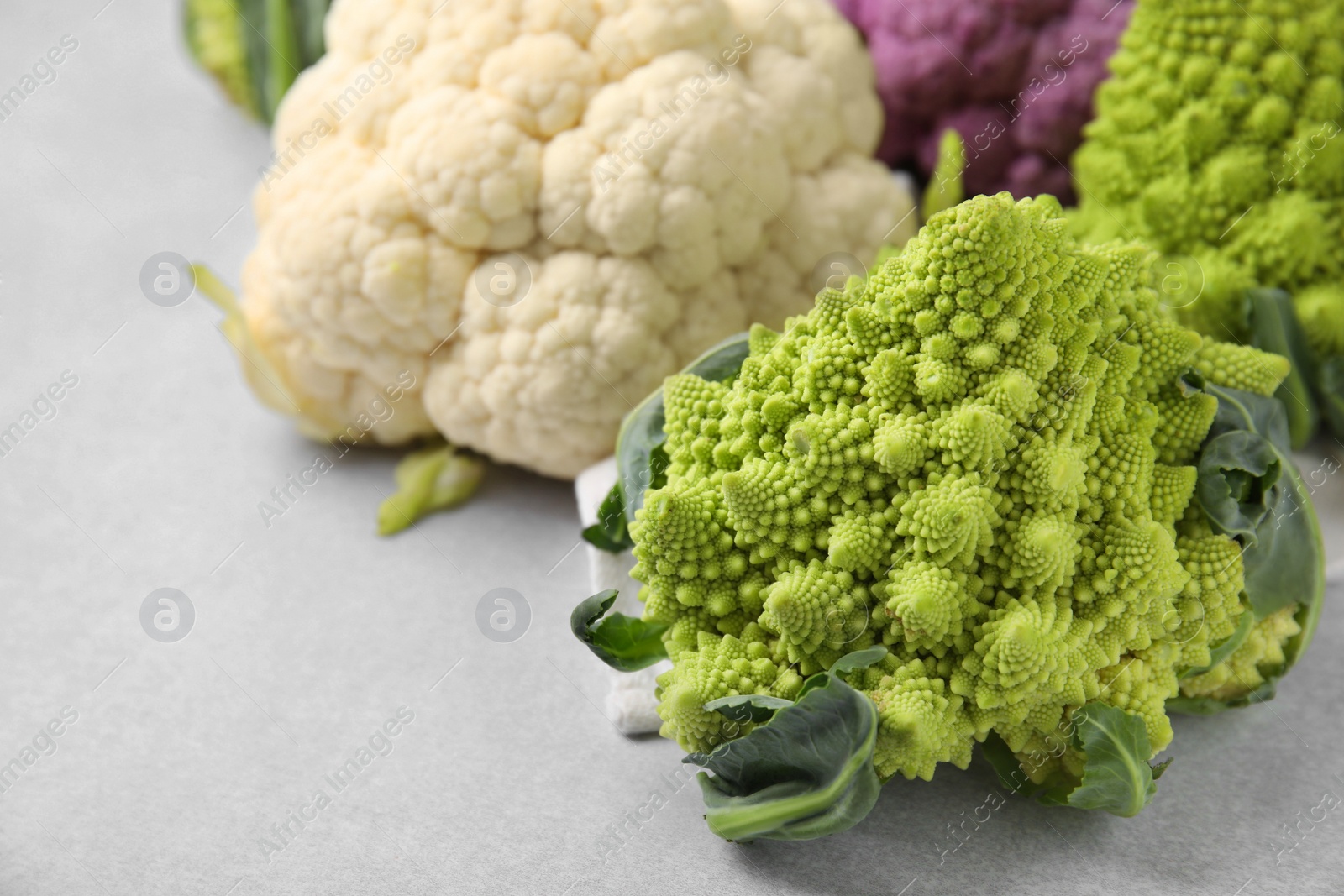 Photo of Different fresh cabbages on white table, closeup. Space for text