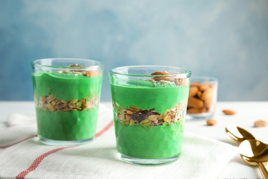 Glass cups of spirulina smoothie on table against color background