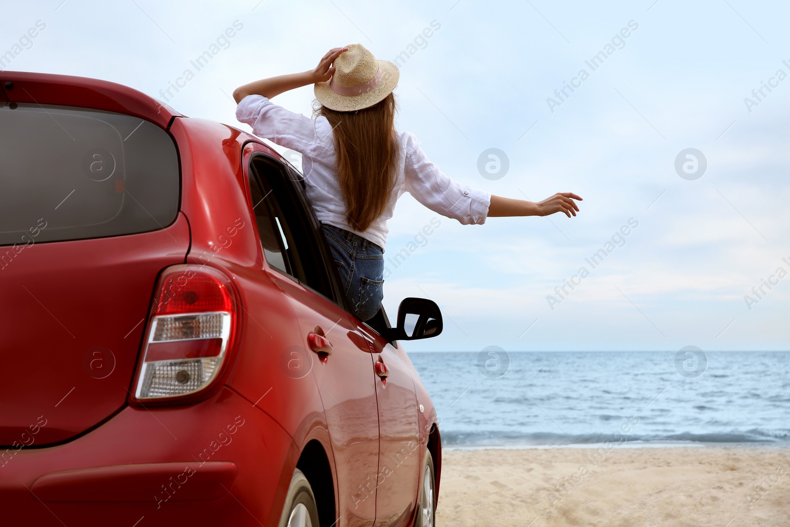 Photo of Happy woman leaning out of car window on beach. Summer vacation trip