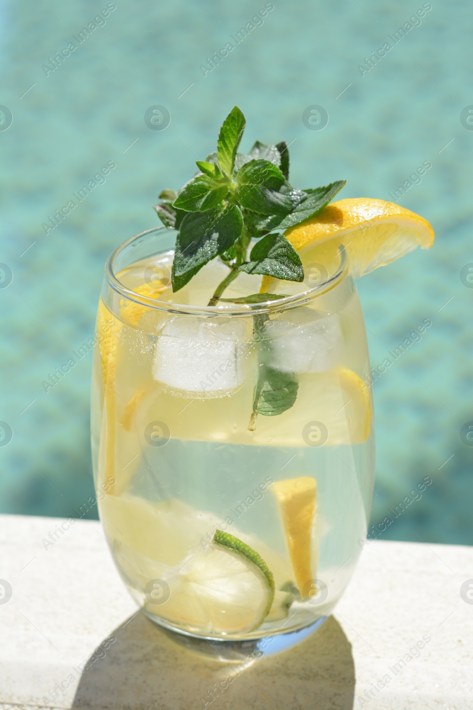 Photo of Refreshing drink with citrus slices and mint near swimming pool