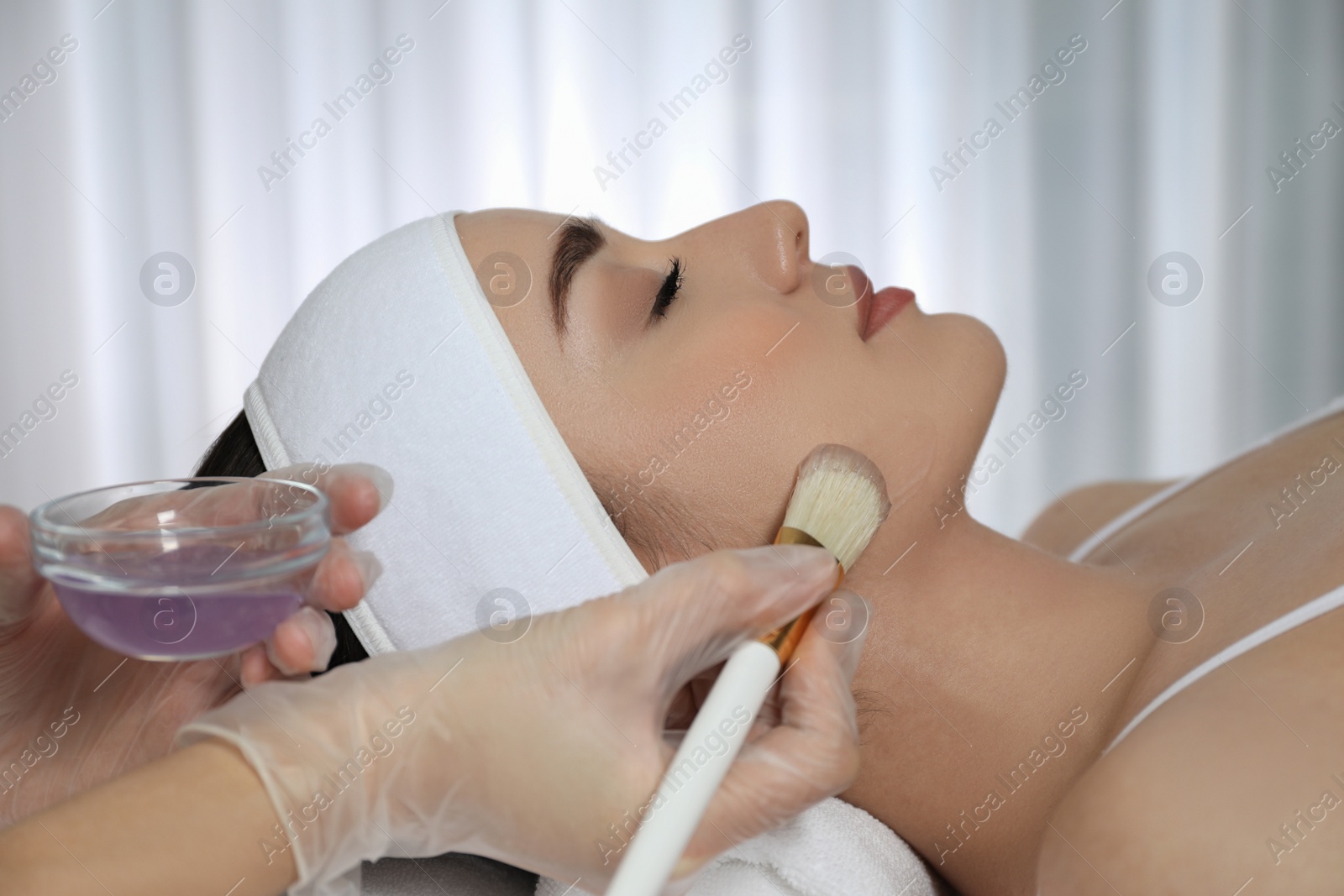 Photo of Young woman during face peeling procedure in salon