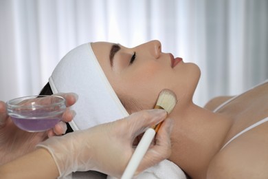 Photo of Young woman during face peeling procedure in salon