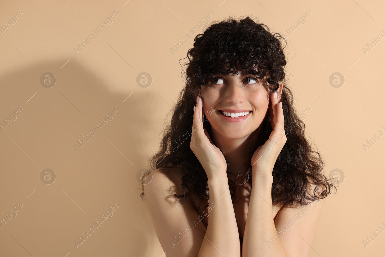 Photo of Portrait of beautiful young woman in sunlight on beige background, space for text