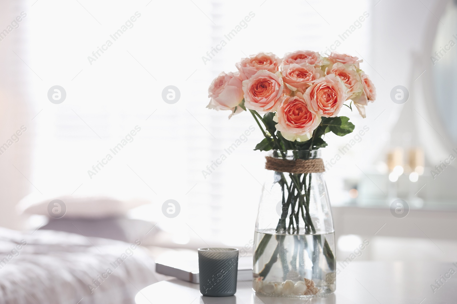 Photo of Glass vase with beautiful flowers on table in modern room interior, space for text