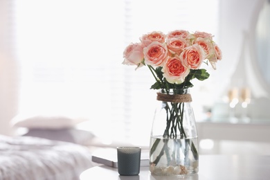 Photo of Glass vase with beautiful flowers on table in modern room interior, space for text