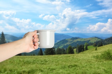 Image of Closeness to nature. Woman holding cup in mountains, closeup