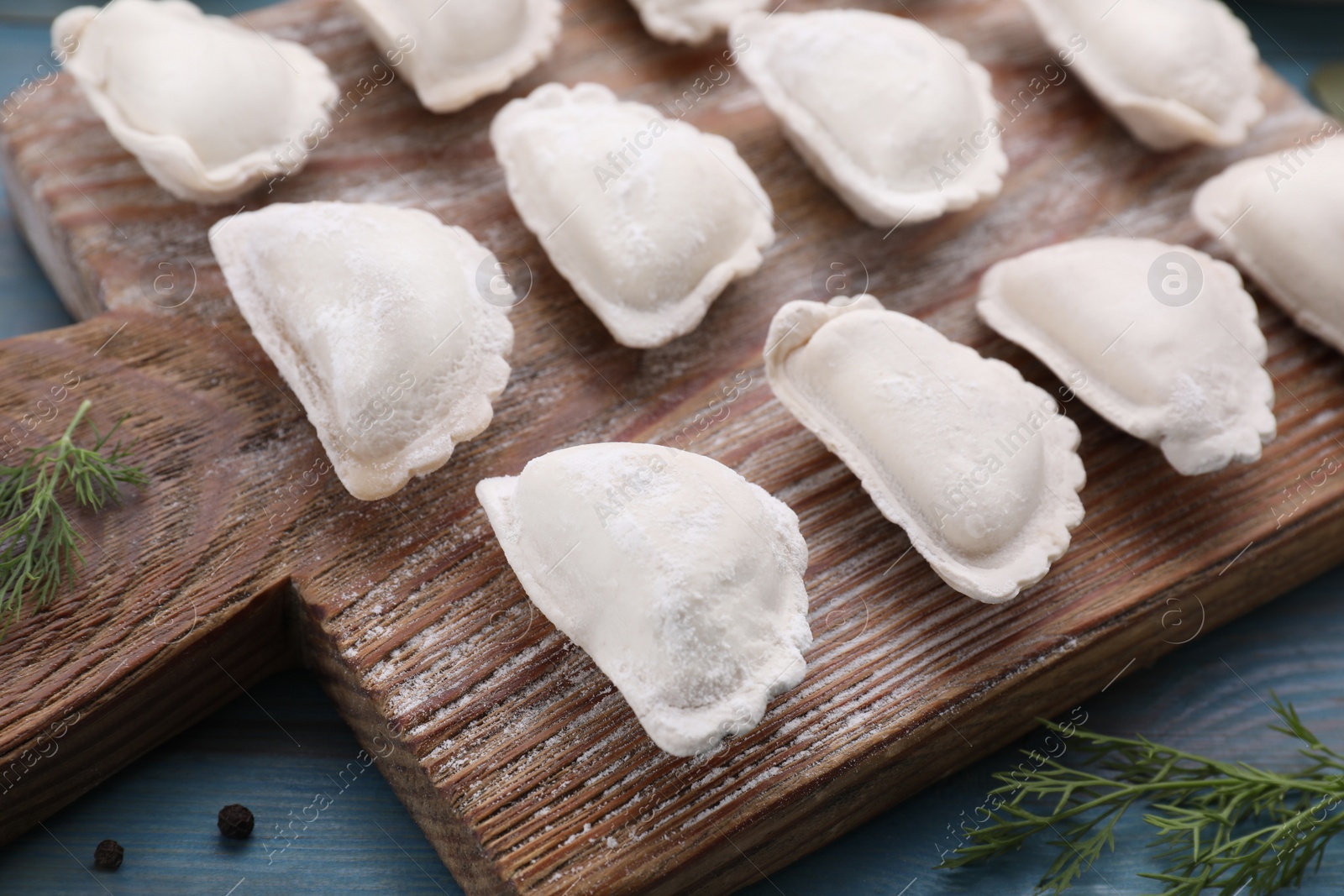 Photo of Raw dumplings (varenyky) on light blue table, closeup