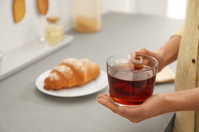 Photo of Woman holding glass cup of tea at home, closeup. Morning routine