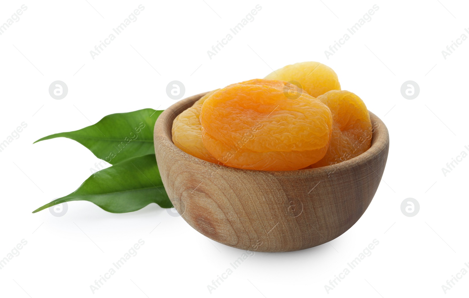 Photo of Wooden bowl with tasty dried apricots and leaves isolated on white