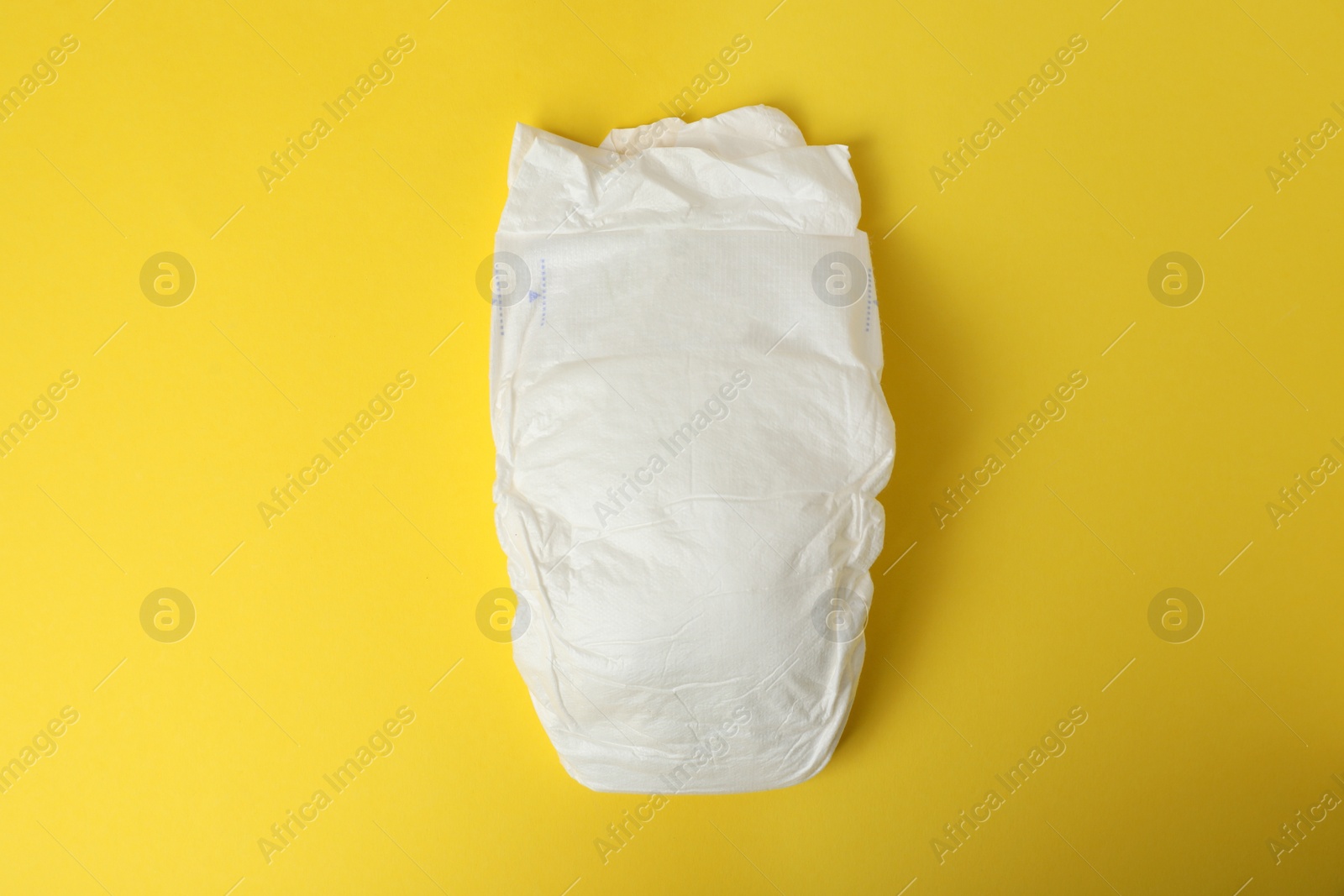 Photo of Baby diaper on yellow background, top view