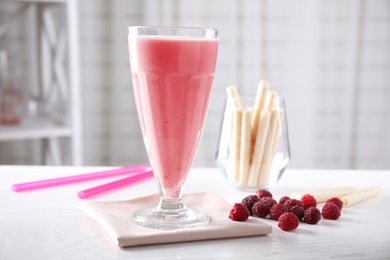 Photo of Tasty milk shake and raspberries on white wooden table